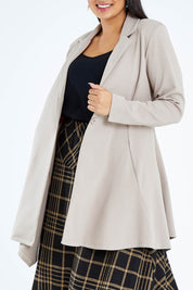 Model Sasha-Lee wearing size 16 of The Asymmetrical Hem Coat in colour String, from the front, cropped image
