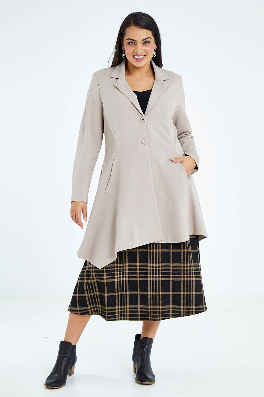 Model Sasha-Lee wearing size 16 of The Asymmetrical Hem Coat in colour String, from the front, showing the whole outfit
