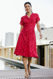 Model Miranda wearing size 10 of The Printed Cotton V Neck Dress in colour Bamboo (Red), from the front, showing the whole outfit