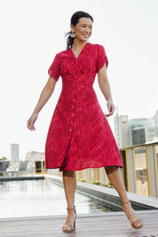 Model Miranda wearing size 10 of The Printed Cotton V Neck Dress in colour Bamboo (Red), from the front, showing the whole outfit