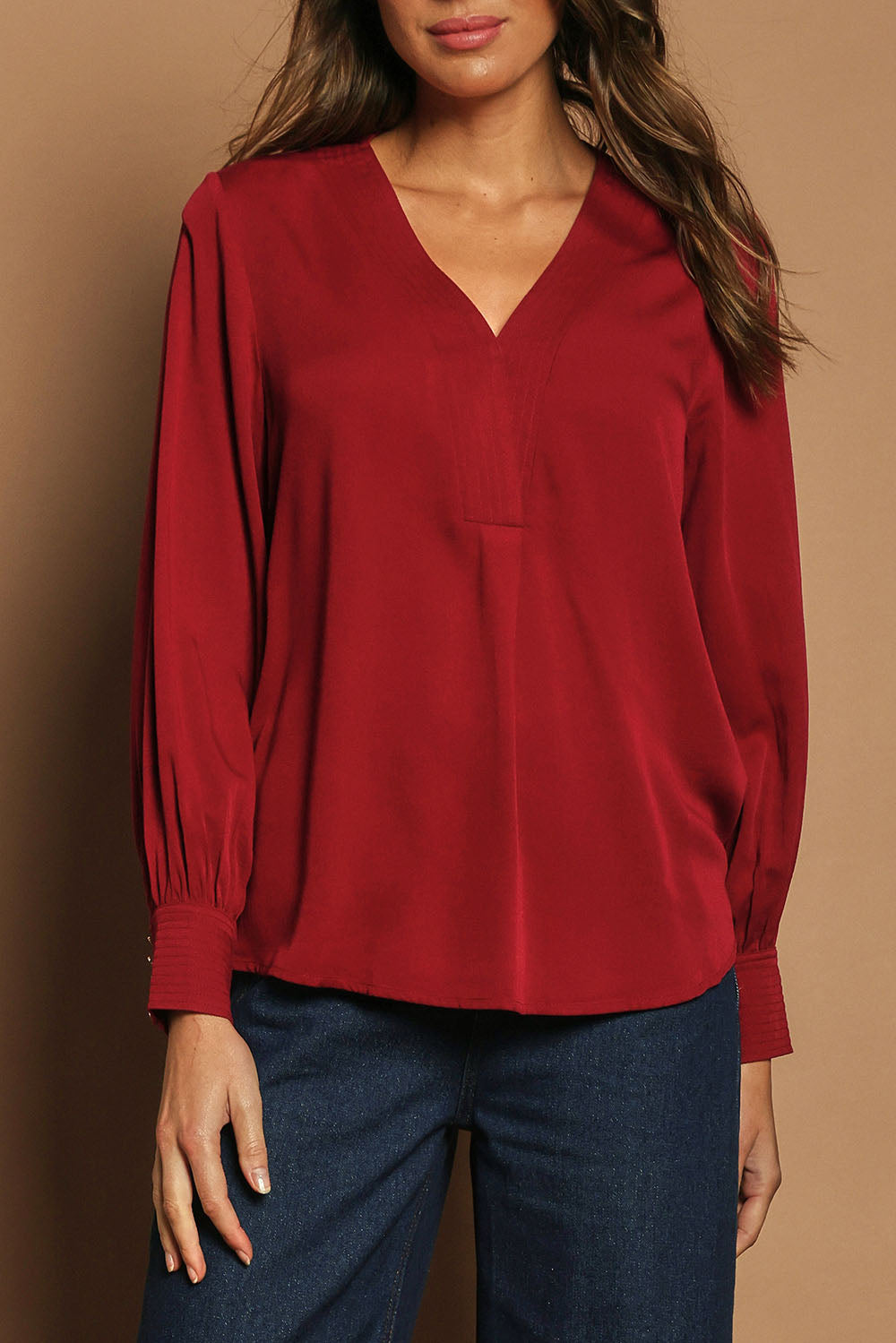 Model Madeline wearing size 10 of The Button Detail Cuff Blouse in colour Garnet (Red), from the front, cropped image