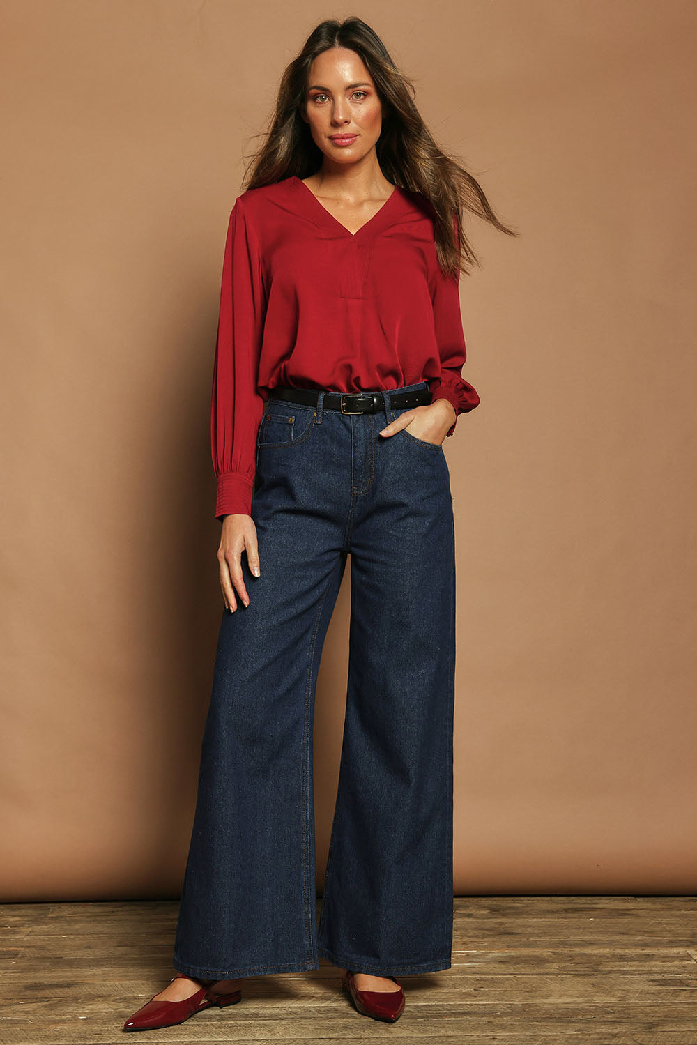 Model Madeline wearing size 10 of The Button Detail Cuff Blouse in colour Garnet (Red), from the front, showing the whole outfit