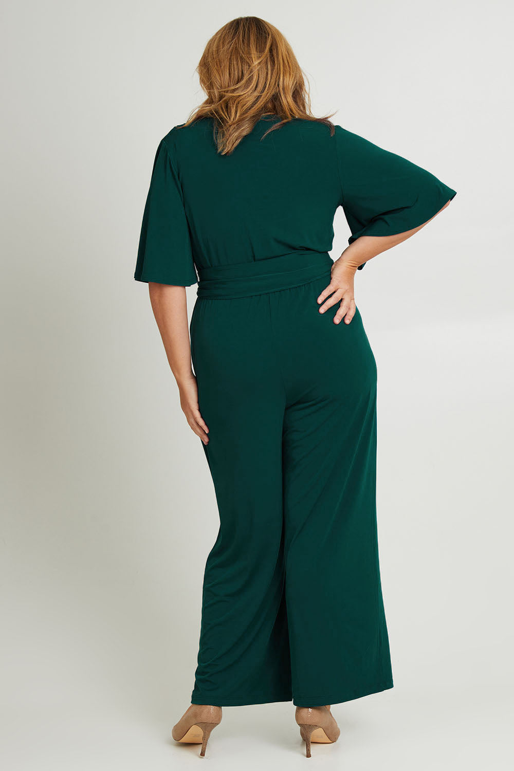 Model Fiona wearing size 16 of The Bell Sleeve Jumpsuit in colour Pine (Green), from the back