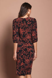 Model Madeline wearing size 10 of The Printed Knot Waist Detail Dress in colour Emberfleur (Black), from the back