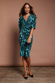 Model Amanda wearing size 10 of The Printed Knot Waist Detail Dress in colour Tealfleur (Green), from the front, showing the whole outfit