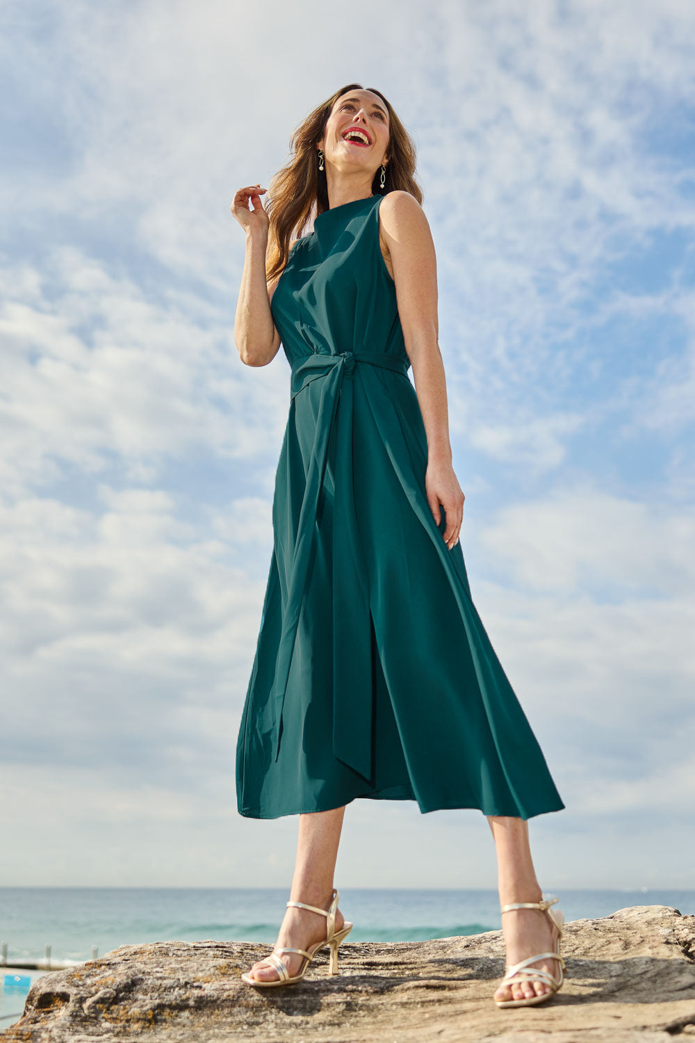 Model Clementine wearing size 10 of The Adore Dress in colour Jewel (Green), from the front, showing the whole outfit