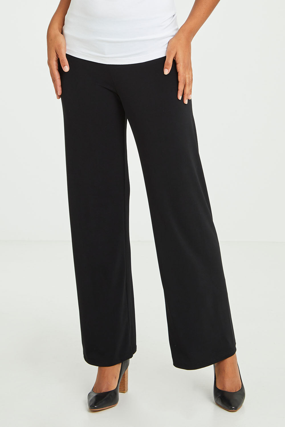 Model Olivia wearing size 10 of The Essential Jersey Pull On Pant in colour Black (Black), from the front, cropped image