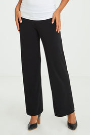 Model Olivia wearing size 10 of The Essential Jersey Pull On Pant in colour Black (Black), from the front, cropped image