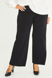 Model Palatina wearing size 16 of The Essential Jersey Pull On Pant in colour Black (Black), from the front, cropped image