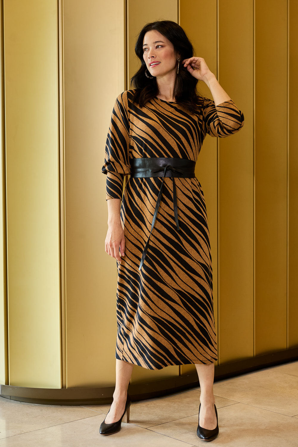 Model Miranda wearing size 10 of The Printed Knit Dress With Belt in colour Abstract (Black), from the front, showing the whole outfit