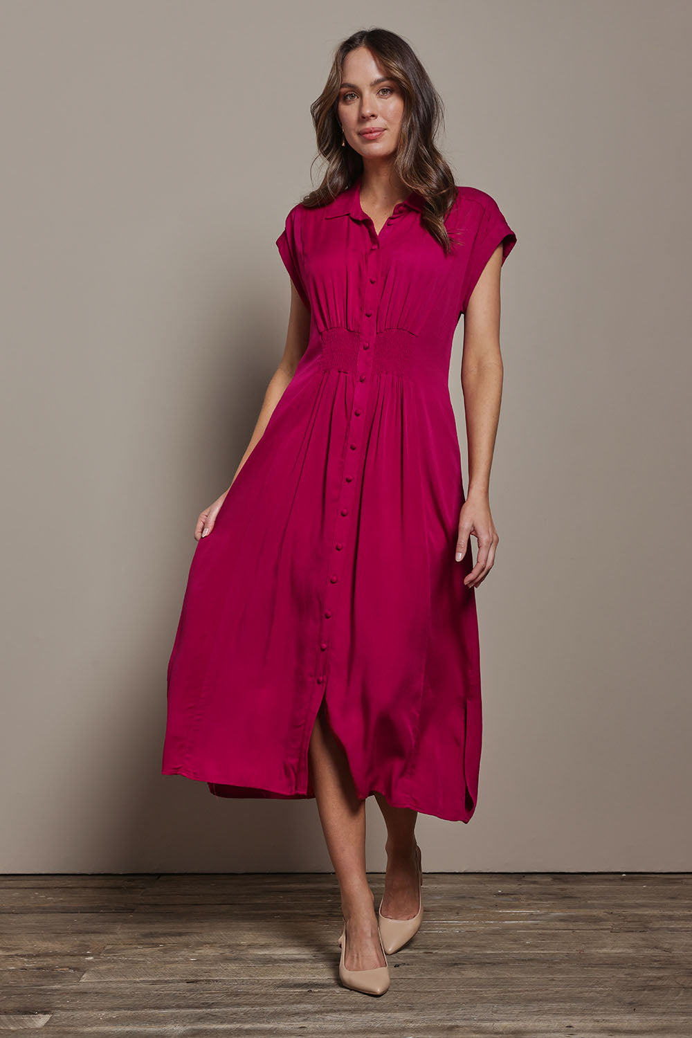 Model Madeline wearing size 10 of The Shirred Waist Detail Dress in colour Raspberry (Red), from the front, showing the whole outfit