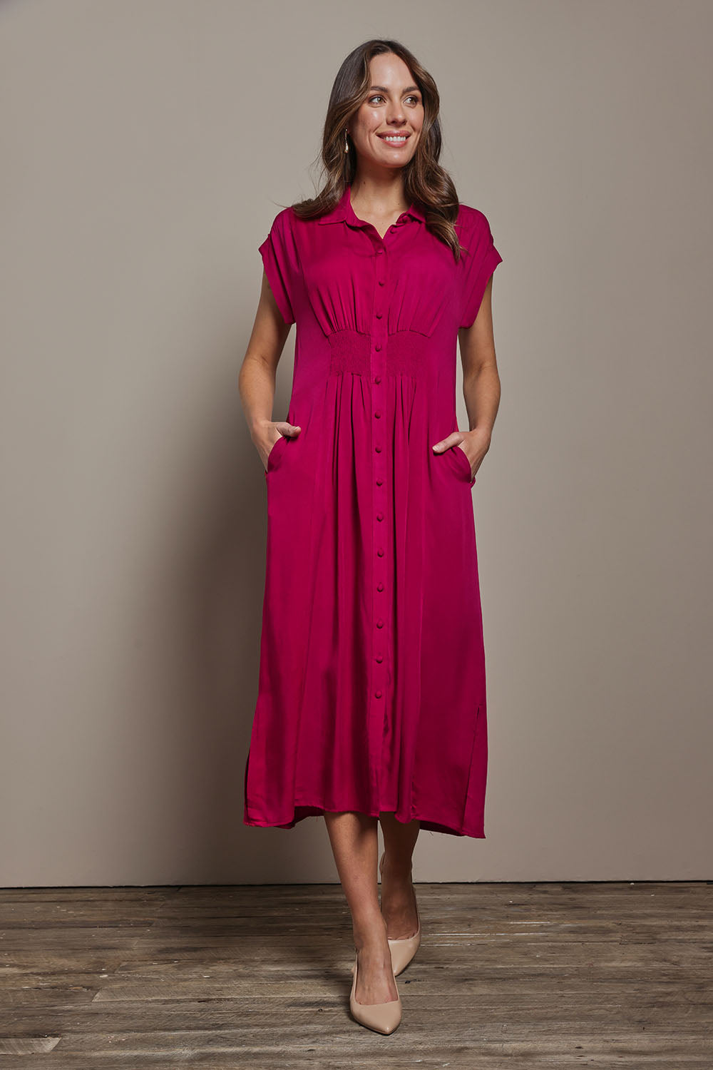 Model Madeline wearing size 10 of The Shirred Waist Detail Dress in colour Raspberry (Red), from the front, showing the whole outfit