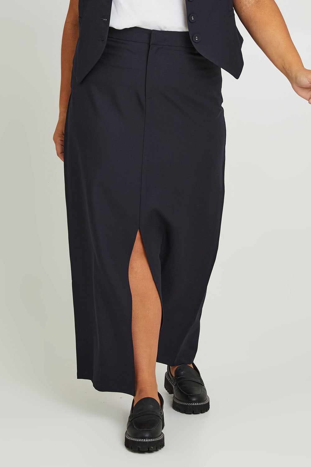 Model Ashleigh wearing size 16 of The Tailored Maxi Skirt in colour Ink (Blue), from the front, cropped image