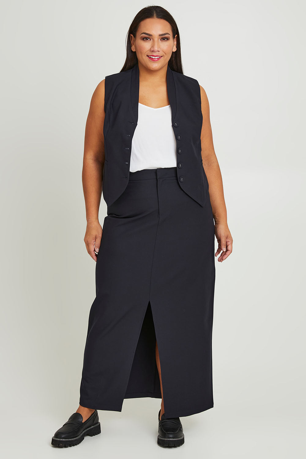 Model Ashleigh wearing size 16 of The Tailored Maxi Skirt in colour Ink (Blue), from the front, showing the whole outfit