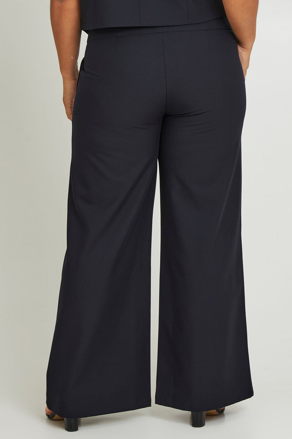 Model Ashleigh wearing size 16 of The Tailored Pant in colour Ink (Blue), from the back