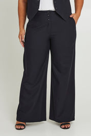 Model Ashleigh wearing size 16 of The Tailored Pant in colour Ink (Blue), from the front, cropped image