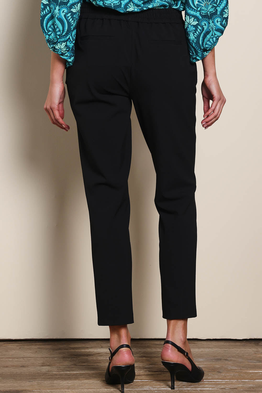 Model Madelinec wearing size 10 of the The Tapered Pull On Stretch Pant – Black in colour Black, from the back