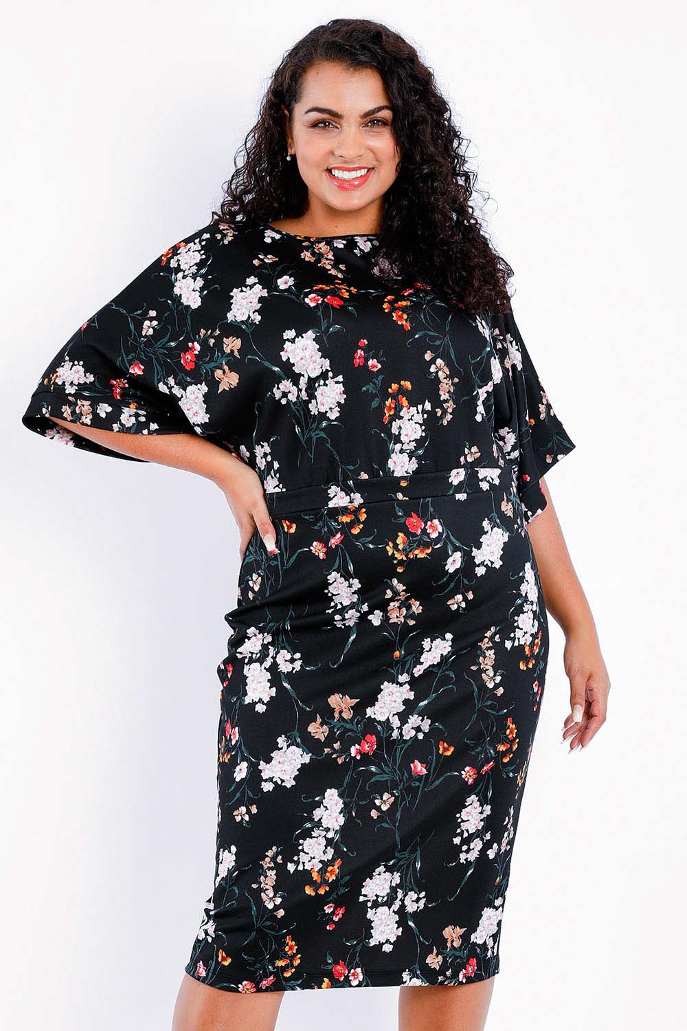 Model Sasha-Lee wearing size 16 of The Printed Kimono Sleeve Pencil Dress in colour Garden (Black), from the front, cropped image