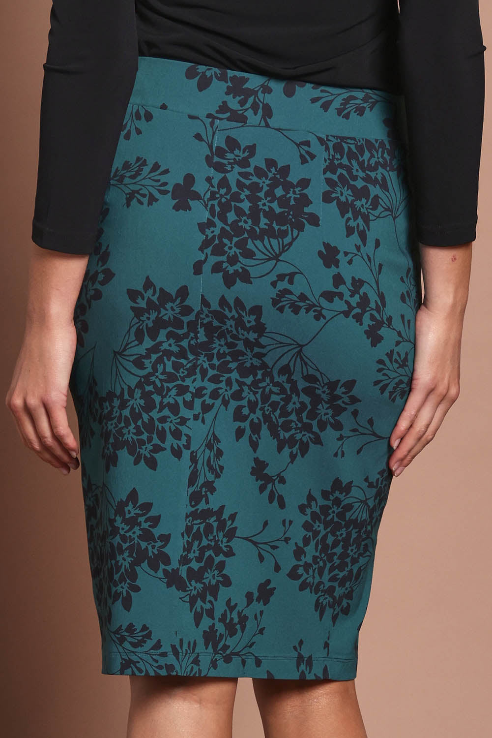 Model Madeline wearing size 10 of The Tube Skirt in colour Tealbloom (Green), from the back
