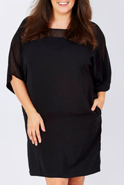 Model Mae wearing size 16 of The Chiffon Mesh Detail Dress in colour Black (Black), from the front, cropped image