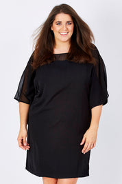 Model Mae wearing size 16 of The Chiffon Mesh Detail Dress in colour Black (Black), from the front, cropped image