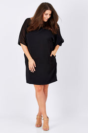 Model Mae wearing size 16 of The Chiffon Mesh Detail Dress in colour Black (Black), from the front, showing the whole outfit