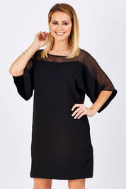 Model Monique wearing size 10 of The Chiffon Mesh Detail Dress in colour Black (Black), from the front, cropped image