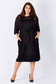 Model Mae wearing size 16 of the Belle Mesh Yoke Dress in colour Back (Black), from the front, showing the whole outfit