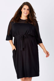 Model Mae wearing size 18 of the Belle Mesh Yoke Dress in colour Back (Black), from the front, cropped image