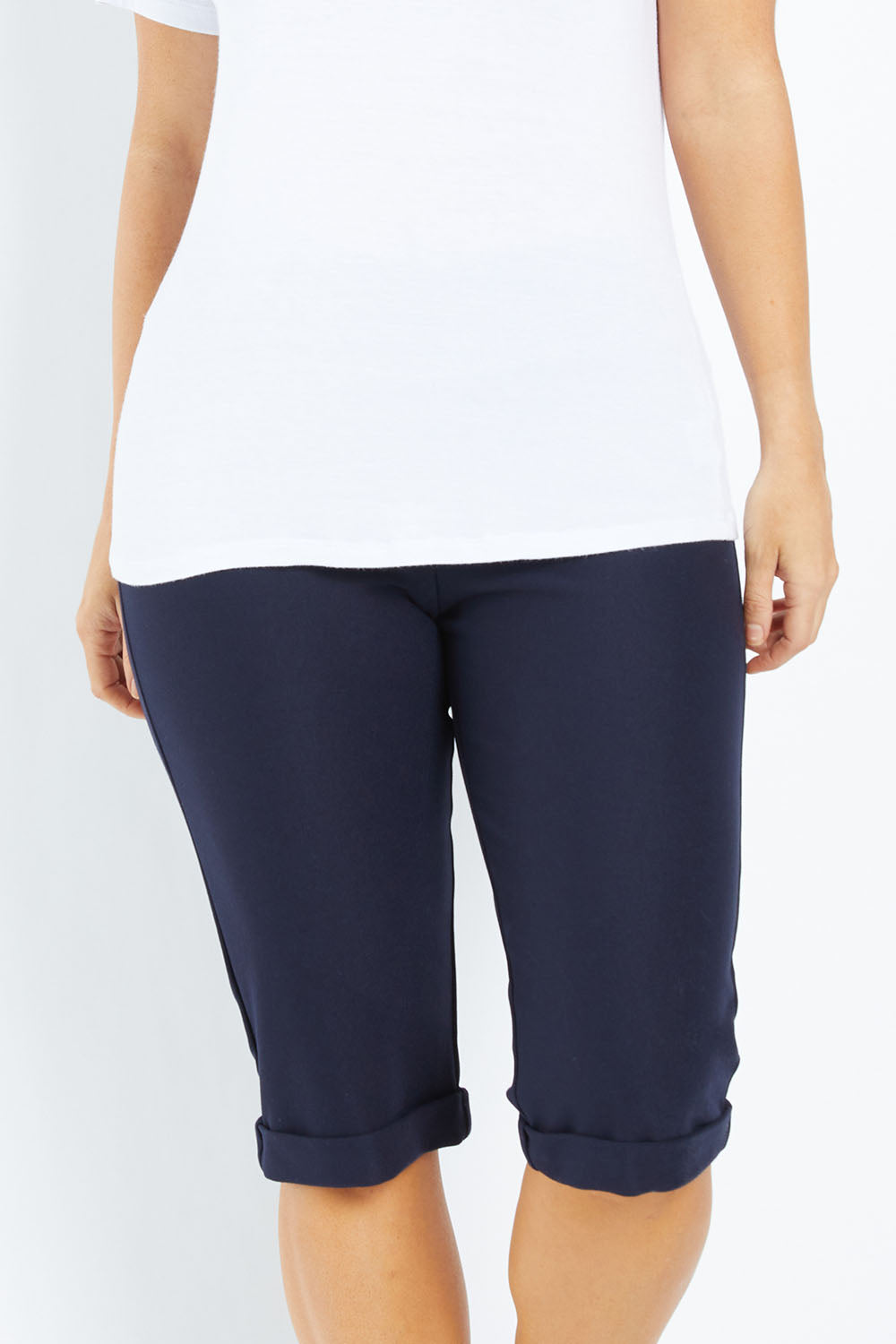 Model Laura wearing size 12 of the Belle Knee Short in colour Navy (Blue), from the front, cropped image