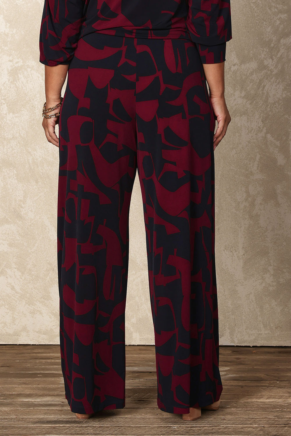 Model Ashleigh wearing size 16 of the Belle Printed Easywear Wide Leg Pant in colour Winenavy (Blue), from the back