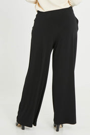 Model Noli wearing size 14 of the Belle Wide Leg Pant in colour Black (Black), from the back