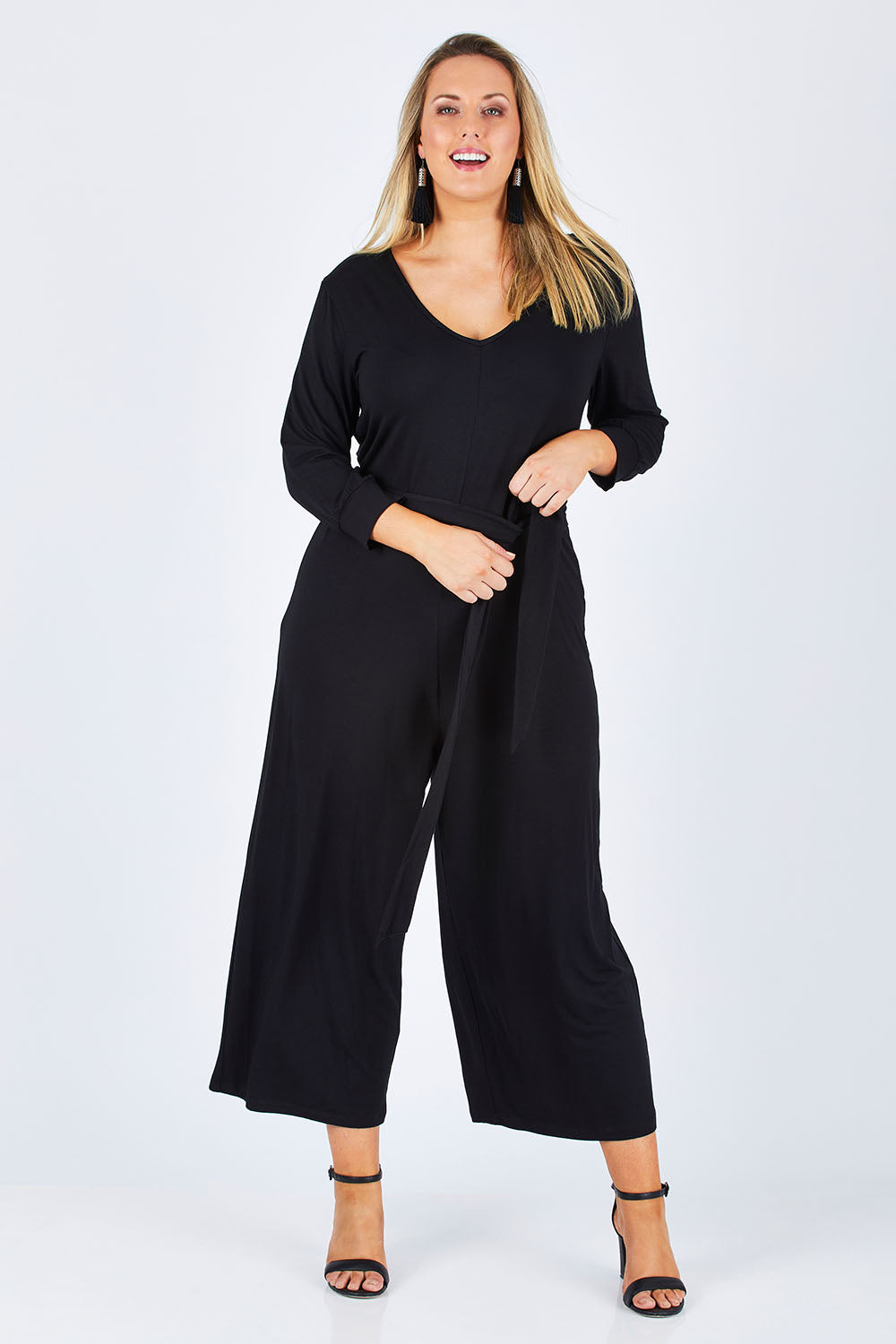 Model Jess wearing size 14 of the Belle 7/8 Sleeve Knit Jumpsuit With Self Belt in colour Black (Black), from the front, showing the whole outfit
