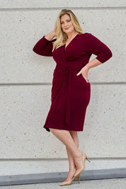 Model Caitlin wearing size 18 of the Belle Basic Wrap Dress in colour Shiraz (Purple), from the front, showing the whole outfit