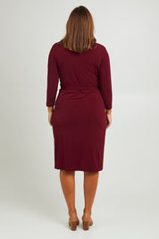 Model Monique wearing size 14 of the Belle Basic Wrap Dress in colour Shiraz (Purple), from the back