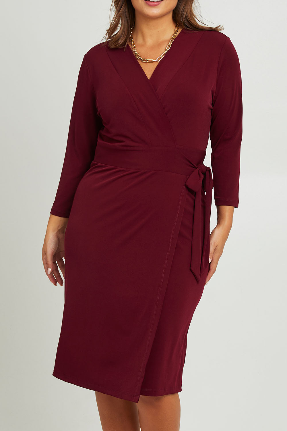 Model Monique wearing size 14 of the Belle Basic Wrap Dress in colour Shiraz (Purple), from the front, cropped image