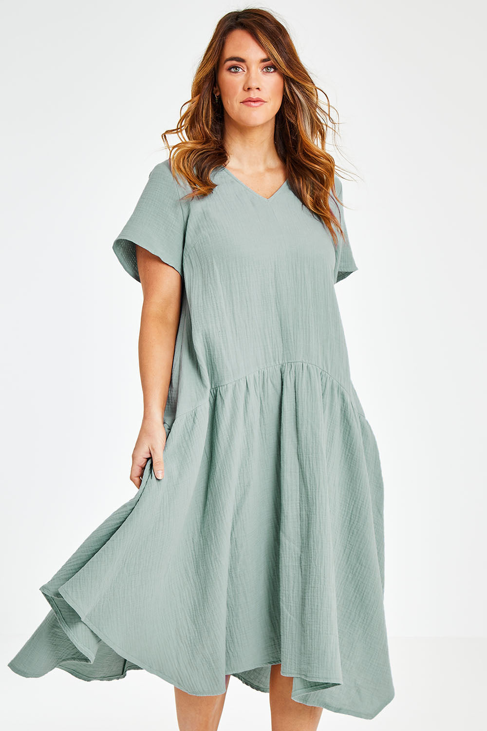 Model Laura wearing size 12 of the Belle Angled Hem Dress in colour Sage (Green), from the front, cropped image