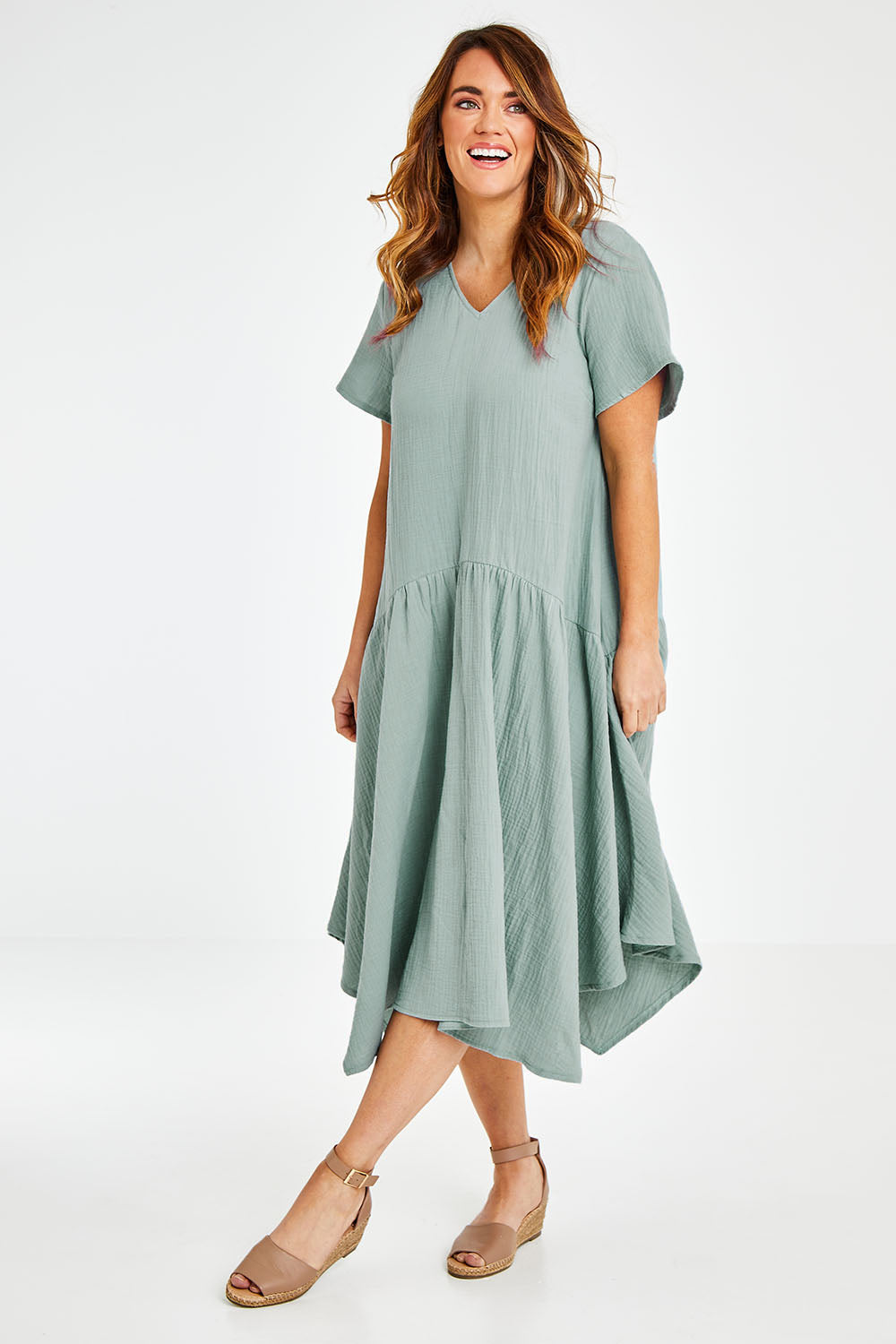 Model Laura wearing size 12 of the Belle Angled Hem Dress in colour Sage (Green), from the front, showing the whole outfit