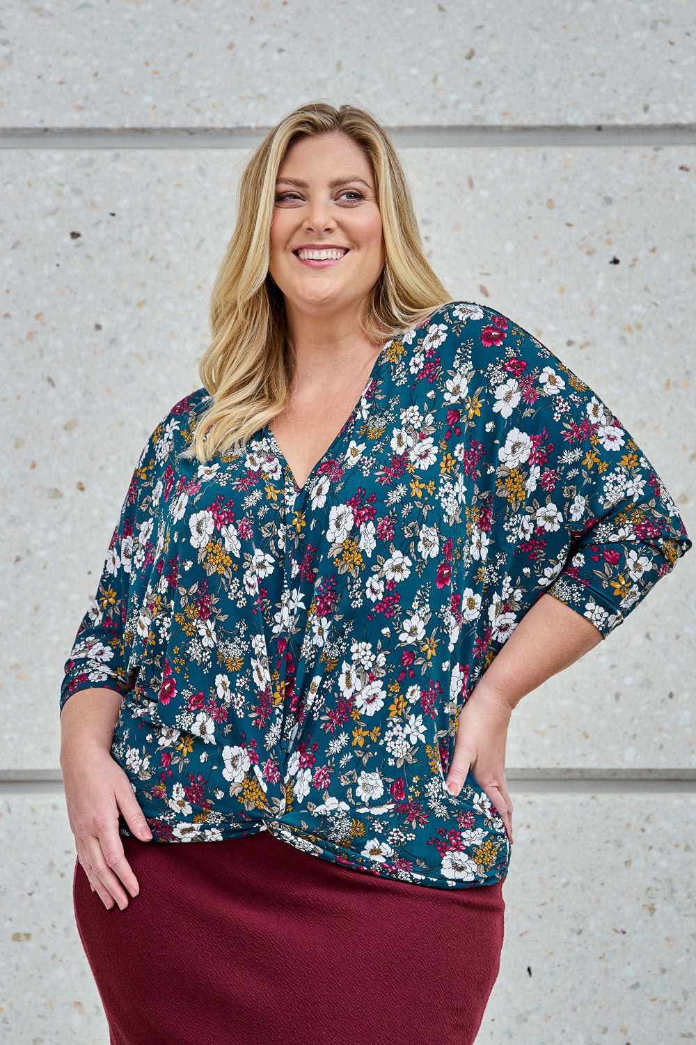Model Caitlin wearing size 18 of the Belle Hip Knot Printed Tee in colour Tealfleur (Green), from the front, showing the whole outfit