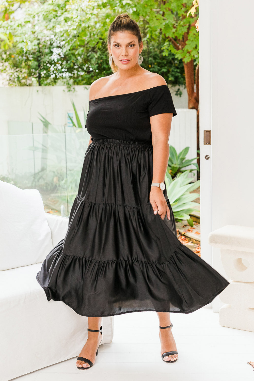Model Palatina wearing size 16 of the Belle Slinky Tiered Skirt in colour Black (Black), from the front, showing the whole outfit