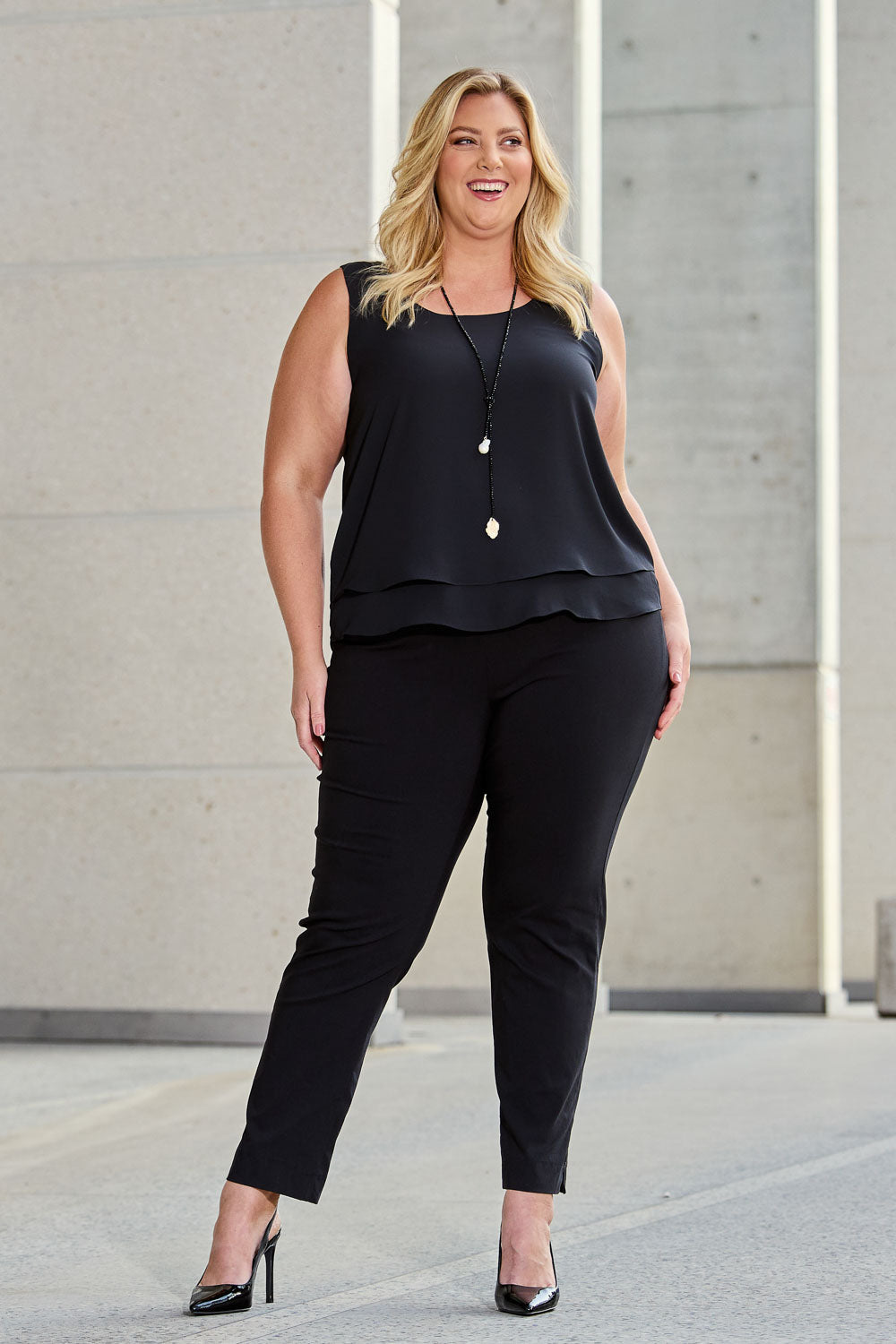 Model Caitlin wearing size 18 of the Belle Essential Pull On Slim Leg Pant in colour Black (Black), from the front, showing the whole outfit