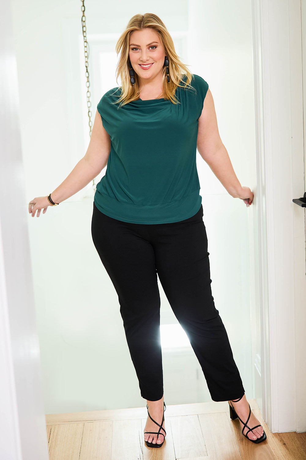 Model Caitlin wearing size 18 of the Belle Essential Pull On Slim Leg Pant in colour Black (Black), from the front, showing the whole outfit