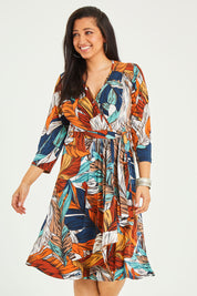 Model Terri-Leigh wearing size 14 of the Belle Faux Long Sleeve Wrap Dress in colour Leafprint (White), from the front, cropped image