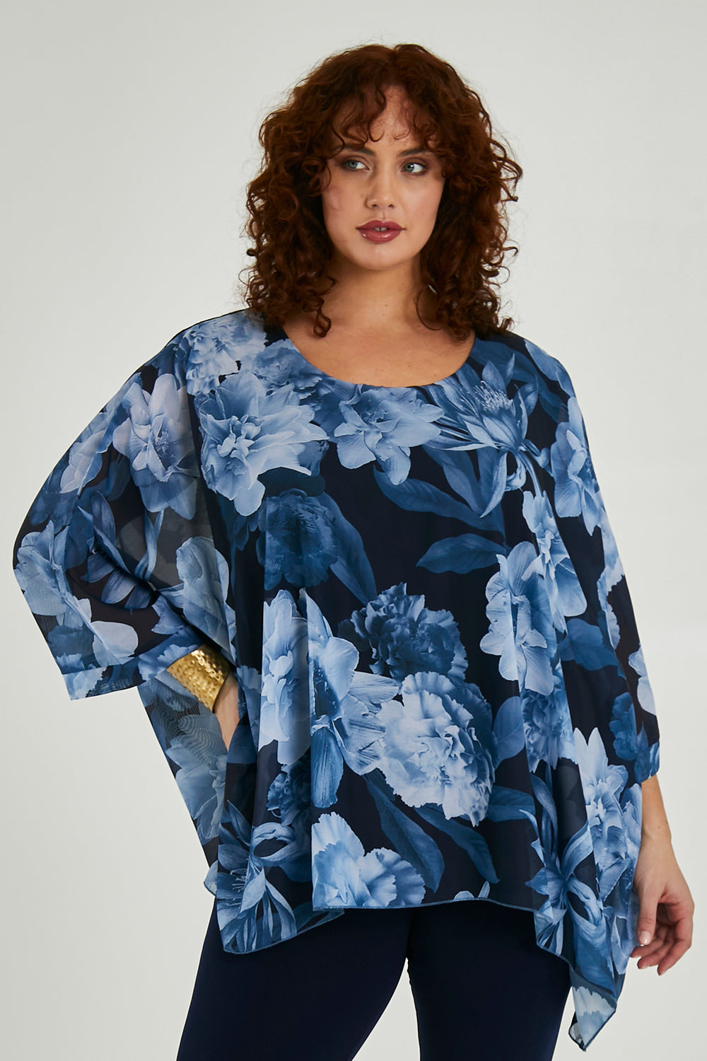 Model Maddy wearing size 16 of the Belle Chiffon Overlay Top in colour Bluefloral (Blue), from the front, cropped image