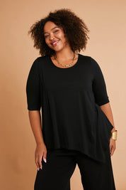 Model Alexis wearing size 16 of the Belle Half Sleeve Forgiver Tunic in colour Black (Black), from the front, showing the whole outfit
