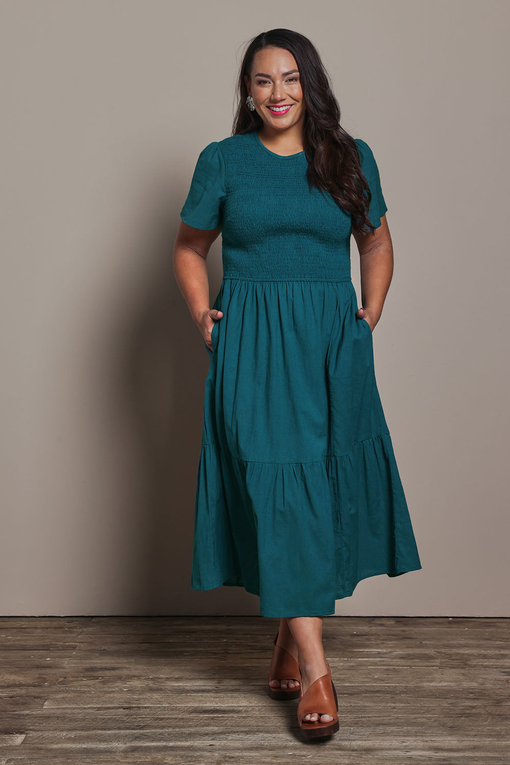 Model Ashleigh wearing size 16 of the Belle Cotton Shirred Bodice Dress in colour Deepocean (Green), from the front, showing the whole outfit