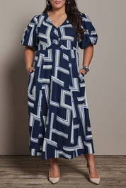 Model Ashleigh wearing size 16 of the Belle Printed Twist Knot Detail Cotton Dress in colour Bluegeo (Blue), from the front, cropped image