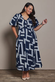 Model Ashleigh wearing size 16 of the Belle Printed Twist Knot Detail Cotton Dress in colour Bluegeo (Blue), from the front, showing the whole outfit