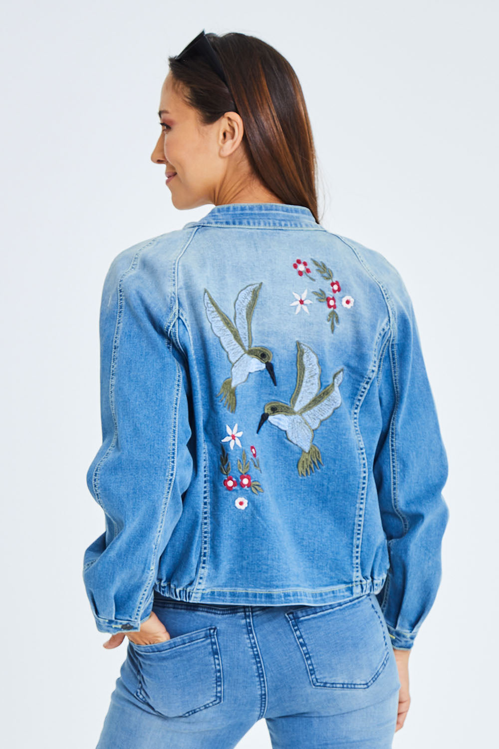 Model Cara wearing size 10 of the Give Me Wings Denim Jacket in colour Denim (Blue), from the back