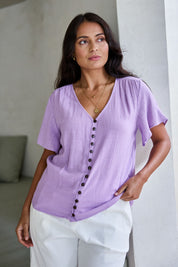 Model Tahnee wearing size 10 of the Cute As A Button Blouse in colour Lavender (Purple), from the front, showing the whole outfit